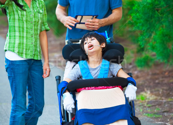 Disabled child in wheelchair outdoors with caregivers or family Stock photo © jarenwicklund