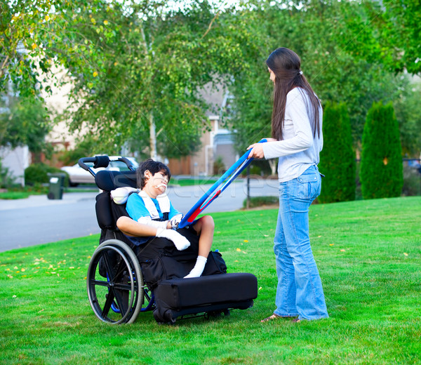 Biracial older sister playing outdoors with disabled little brot Stock photo © jarenwicklund
