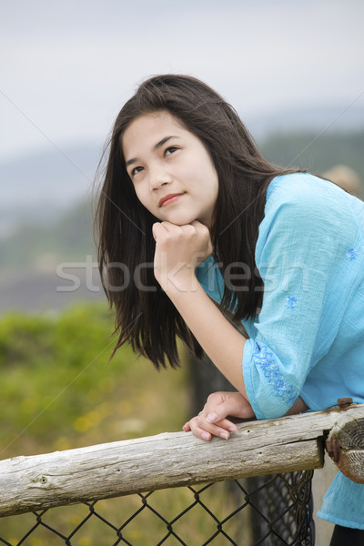 Stock photo: Preteen biracial girl by ocean shore with a thoughtful look, loo