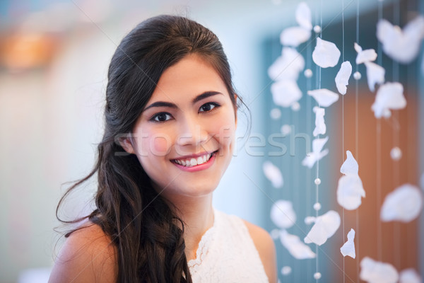 Stock photo: Beautiful biracial bride smiling next to curtain of white rose p