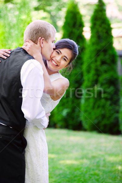 Caucasian groom lovingly kissing his biracial bride on cheek. Di Stock photo © jarenwicklund