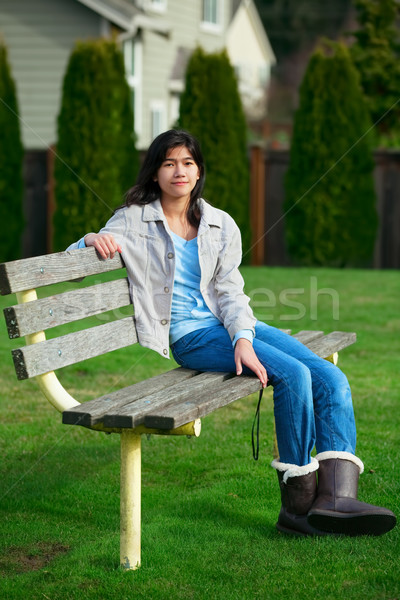 Young biracial teen girl relaxing outdoors on park bench Stock photo © jarenwicklund