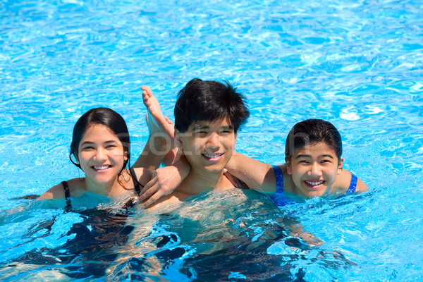 Drie teen broers en zussen glimlachend samen zwembad Stockfoto © jarenwicklund