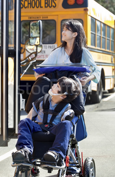 Stock photo: Big sister pushing disabled brother in wheelchair at school