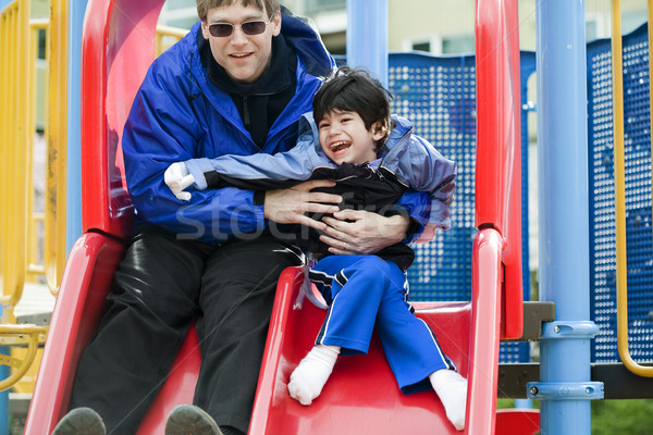 Father going down slide with disabled son who has cerebral palsy Stock photo © jarenwicklund