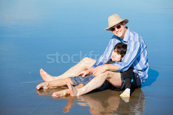 Father playing with disabled son on beach, holding him upright Stock photo © jarenwicklund
