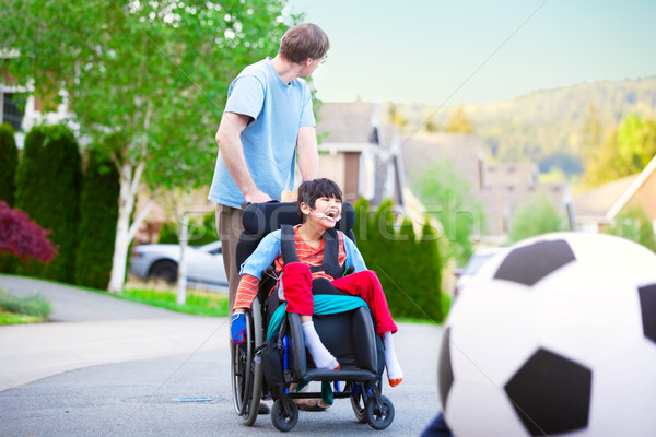 Caucasian father helping disabled biracial son in wheelchair pla Stock photo © jarenwicklund