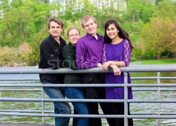 Stock photo: Four young multiethnic friends together outdoors by lake