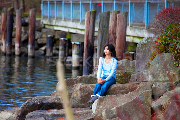 Young teen girl sitting on large boulders along lake shore, look Stock photo © jarenwicklund