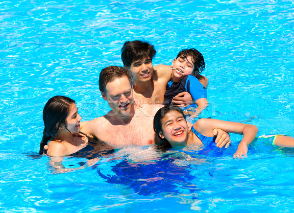 Multiracial family swimming together in pool. Disabled youngest  Stock photo © jarenwicklund