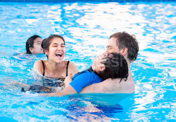 Multiracial family swimming together in pool. Disabled youngest  Stock photo © jarenwicklund