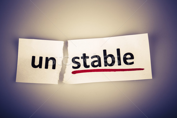 Stock photo: The word unstable changed to stable on torn paper