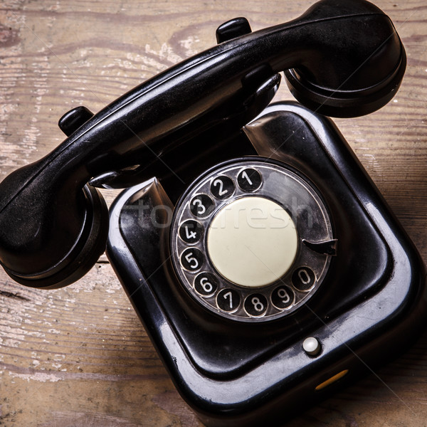 Stock photo: Old black phone with dust and scratches on wooden floor