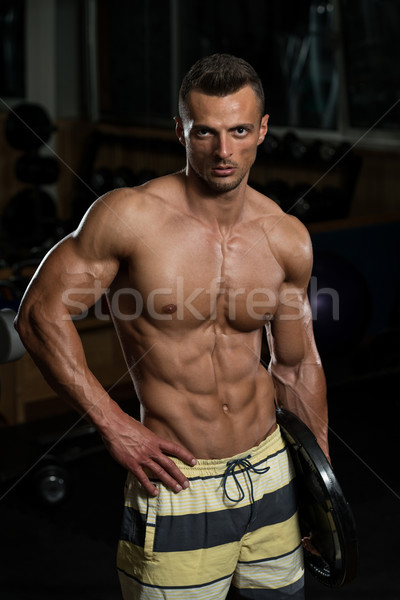 Young Muscular Men Holding Weight In His Arm Stock photo © Jasminko