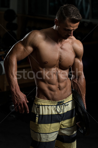 Sexy Muscular Man Holding Weight In His Arm Stock photo © Jasminko