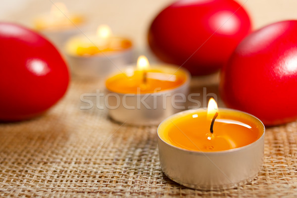 Closeup of rounded candles placed between three red egg Stock photo © jaycriss