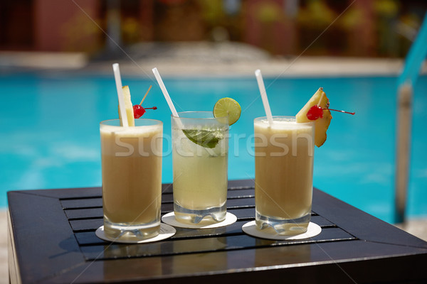 Cocktails of Mojito and  Pina Colada on Wooden Table Near the Swimming Pool Stock photo © jirivondrous