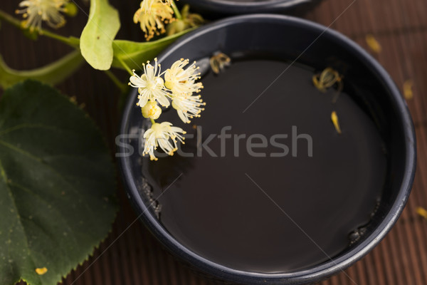 Stock photo: teapot and cup with linden tea and flowers