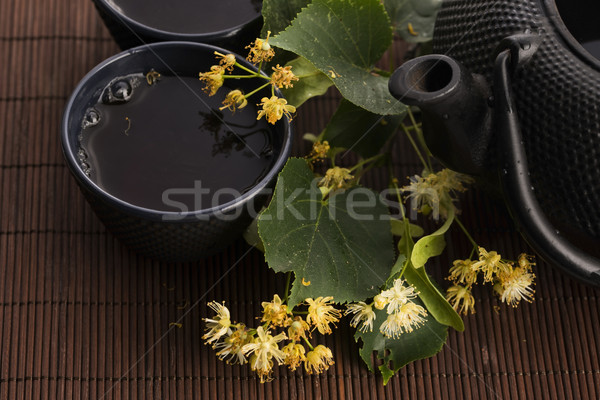 teapot and cup with linden tea and flowers Stock photo © joannawnuk