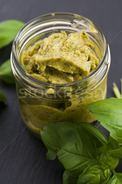 Glass jar with basil pesto on a black plate Stock photo © joannawnuk