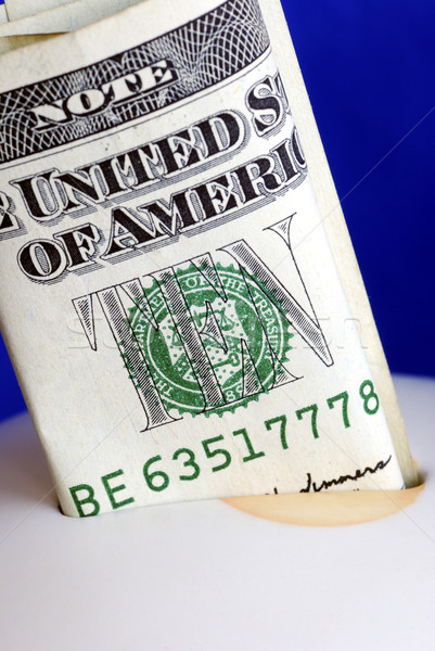 Deposit ten dollars into the piggy bank isolated on blue Stock photo © johnkwan