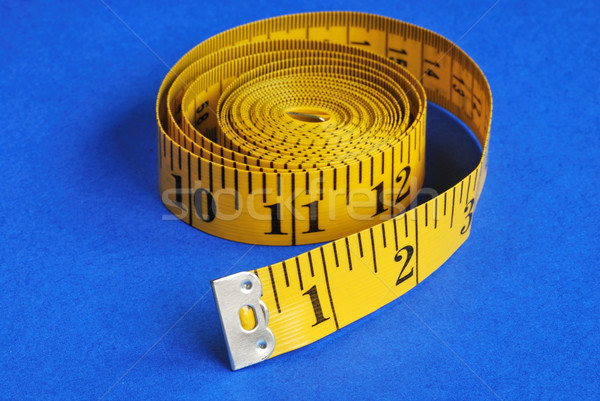 A coiled-like measuring tape isolated on blue background Stock photo © johnkwan