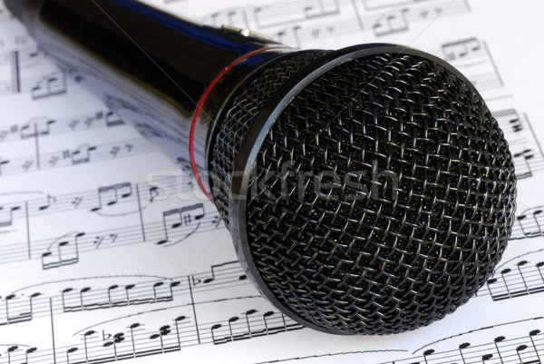 A black microphone on the top of music sheets Stock photo © johnkwan