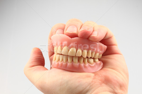 Zęby proteza ludzka ręka odizolowany biały uśmiech Zdjęcia stock © jonnysek
