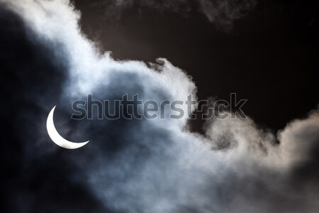 Partial solar eclipse through clouds Stock photo © Juhku