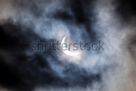Partial solar eclipse through clouds Stock photo © Juhku