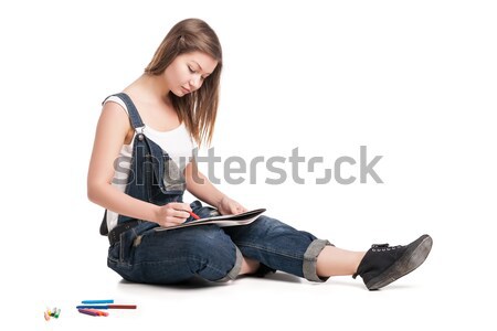 Young woman happily sitting  on the floor drawing in her note pad Stock photo © julenochek