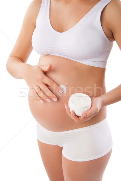 Pregnant woman with cosmetic cream on belly Stock photo © julenochek