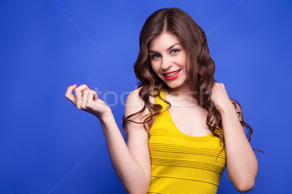Cheerful model in yellow dress pulling her hair Stock photo © julenochek