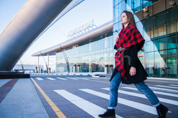 Young woman walking across pedestrian crossing against of airport building Stock photo © julenochek