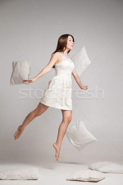 Woman in white dress in mid air with flying pillow Stock photo © julenochek
