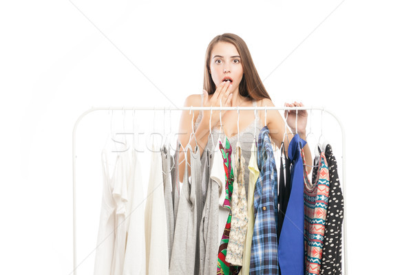 Brunette covering mouth in surprise near hanger with clothes Stock photo © julenochek