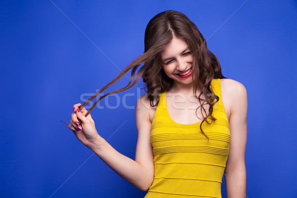 Cheerful model in yellow dress pulling her hair Stock photo © julenochek