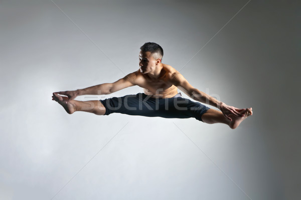 Caucasian man gymnastic leap posture on grey Stock photo © julenochek