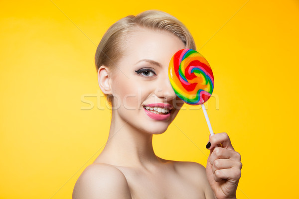 Model covering eye with lollipop and smiling at camera Stock photo © julenochek