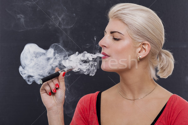 Stock photo: Stylish blond woman smoking an e-cigarette