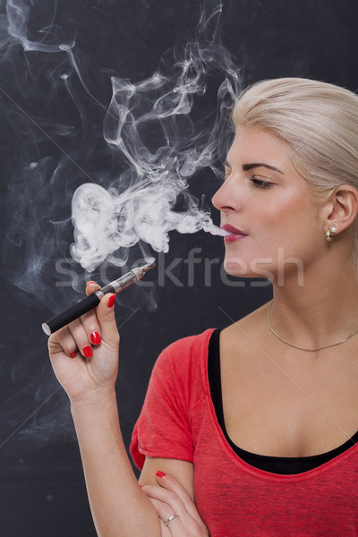 Stylish blond woman smoking an e-cigarette Stock photo © juniart