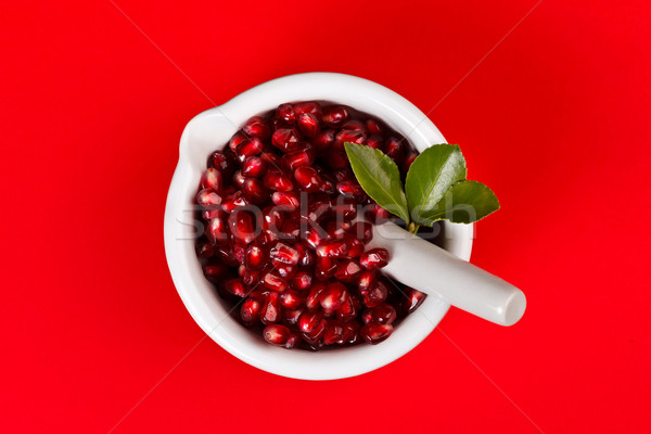 Grenadine seeds in a mortar on red Stock photo © kalozzolak
