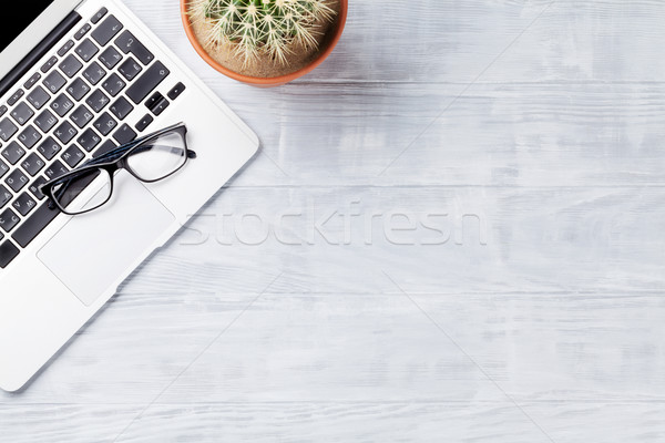 Desk table with laptop, glasses and cactus plant Stock photo © karandaev