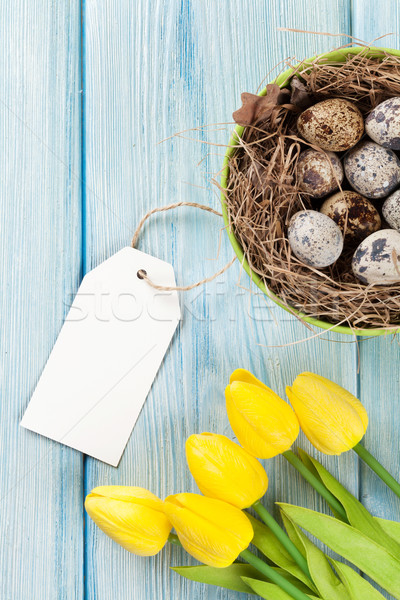 Huevos de Pascua amarillo tulipanes nido azul mesa de madera Foto stock © karandaev