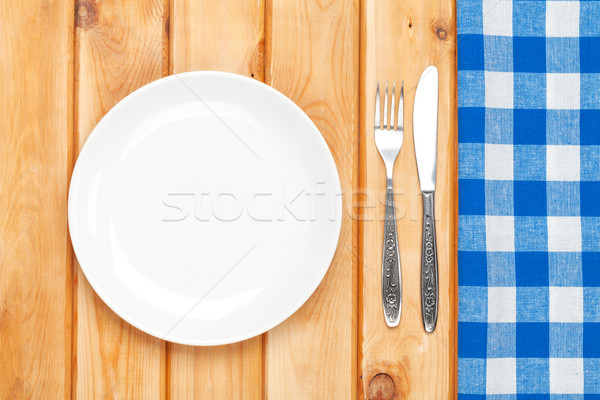 Empty plate, silverware and towel over wooden table background Stock photo © karandaev