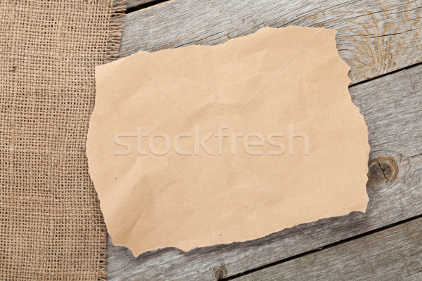 Old paper piece and burlap on wooden textured background Stock photo © karandaev
