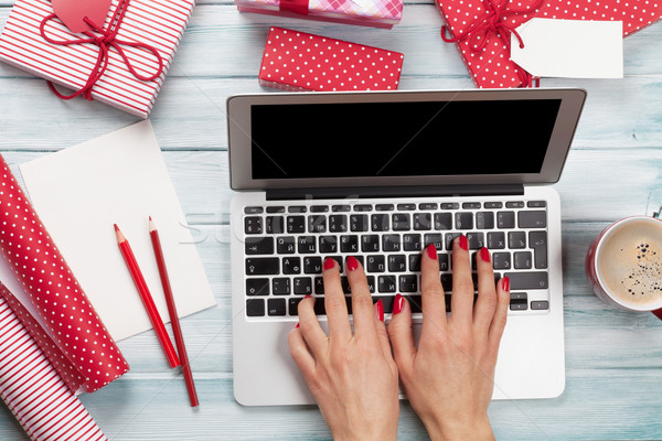 Female working on laptop and wrapping christmas gifts Stock photo © karandaev
