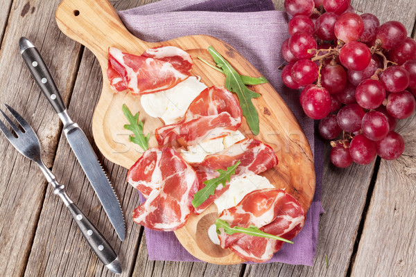 Prosciutto and mozzarella on board and grape Stock photo © karandaev