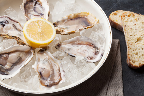 Opened oysters and lemon over ice Stock photo © karandaev