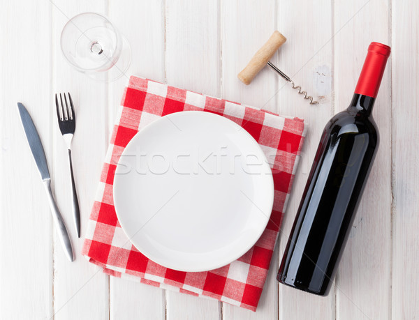 Table setting with empty plate, wine glass and red wine bottle Stock photo © karandaev
